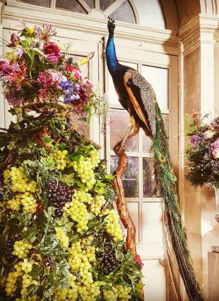 a taxidermy peacock with an extravagant bouquet of flowers