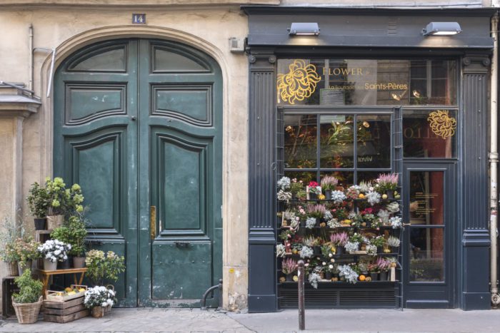 a green-blue door next to a florist in paris
