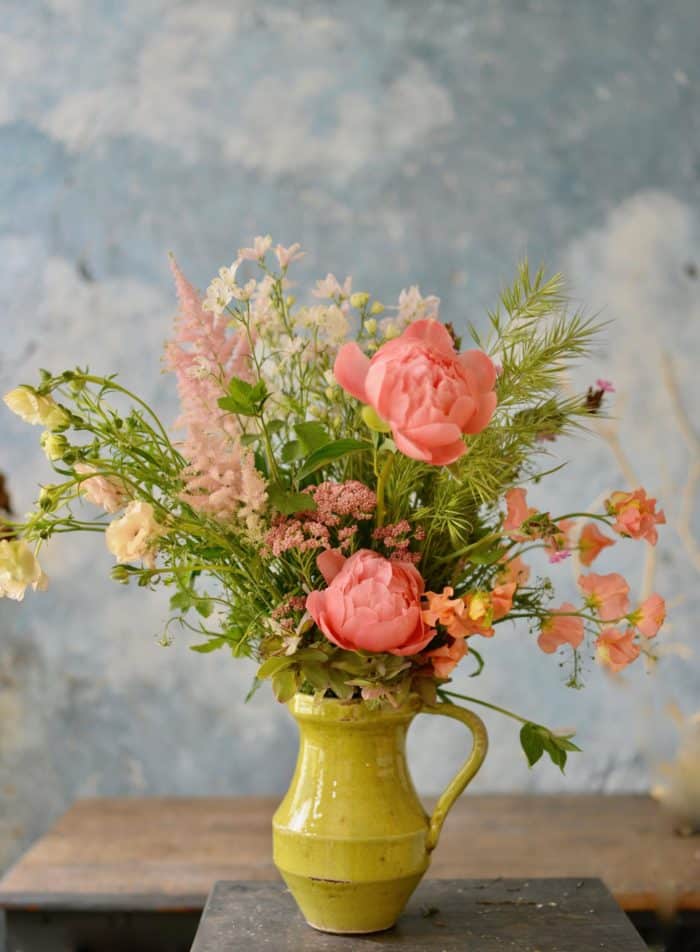 a brightly colored bouquet in a mustard yellow vase