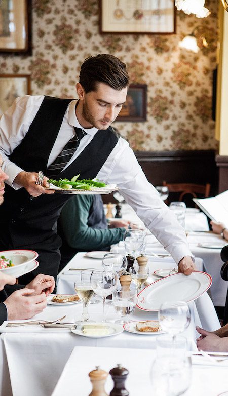 a waiter serving food in Allard by Alain Ducasse