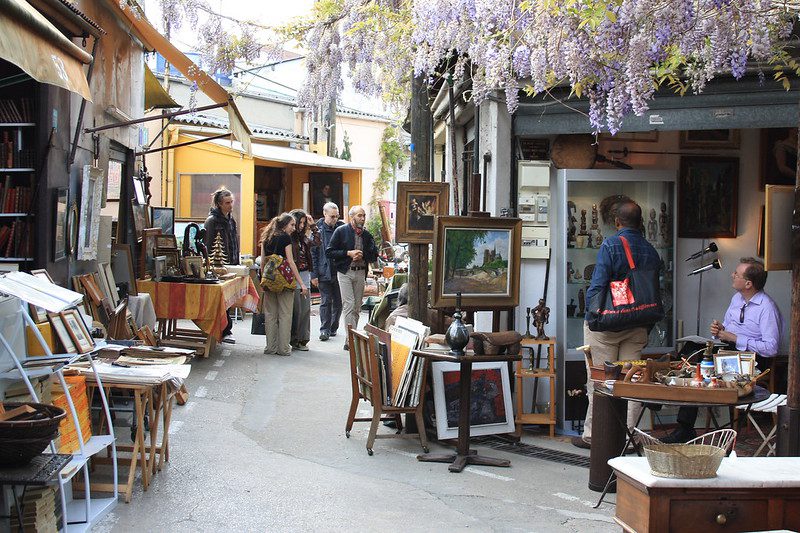 french antique market stalls with artwork under wisteria at Saint Ouen