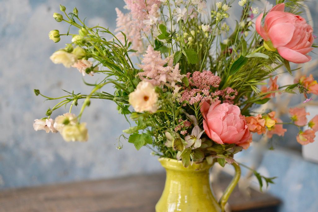 a country bouquet with poenies in a mustard yellow jug