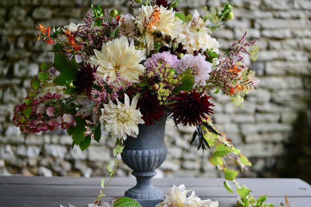 a bouquet filled with dahlias in a stone urn