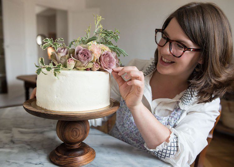 woman decorating a cake with flowers
