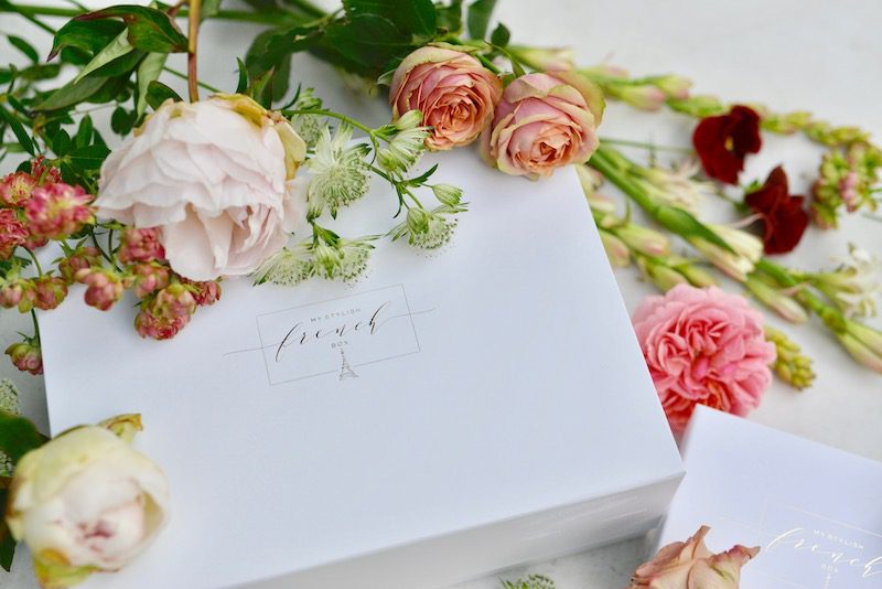 white box with logo surrounded by pink and green flowers