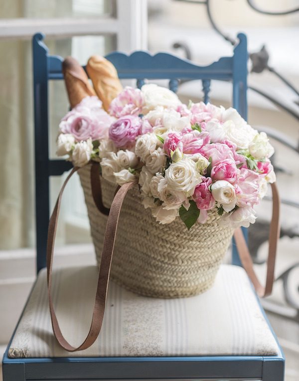 a wicker basket of roses and two baguettes