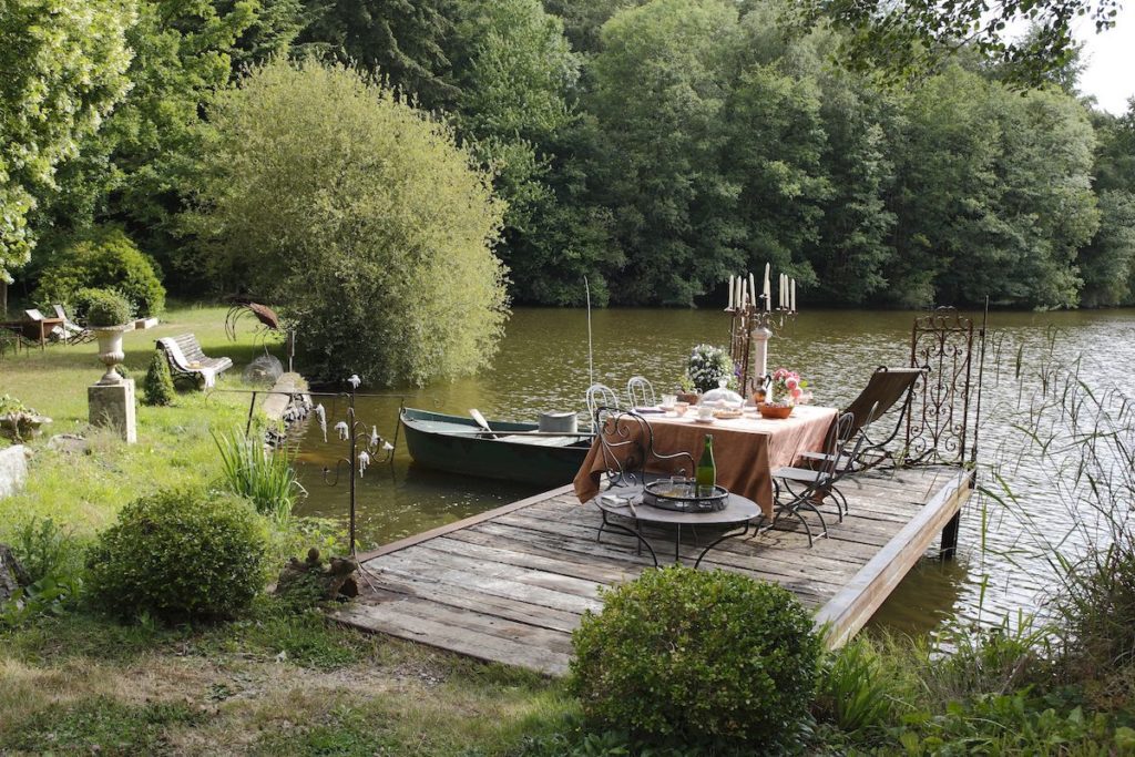 a pontoon with a dressed table ready for lunch, beside a lake