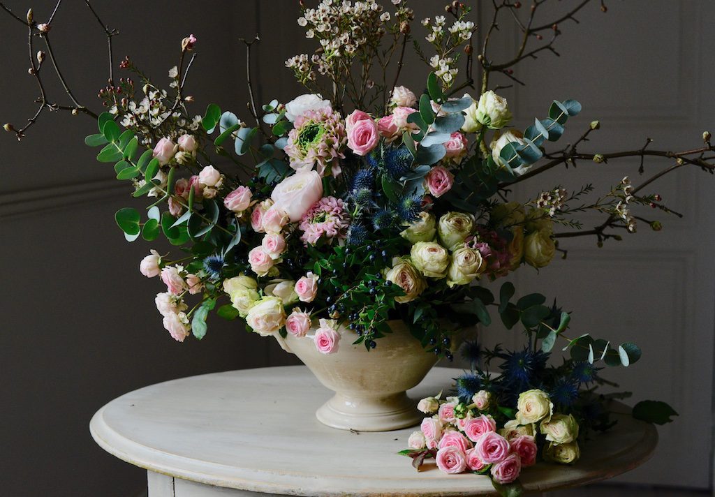 a bouquet filled with roses, ranunculus on a small table 