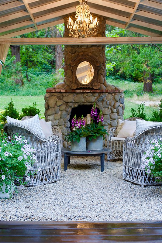 outdoor stone fireplace with two armchairs and chandelier