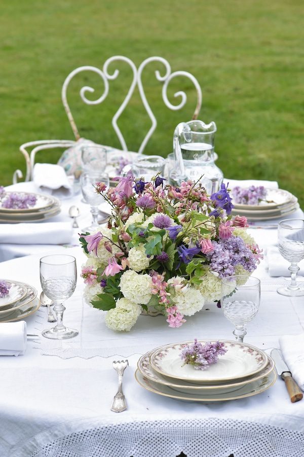 french tablescape on lawn with white tablecloth and bouquet in center