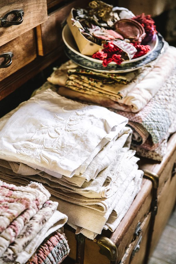 piles of vintage linens stacked on ancient chests