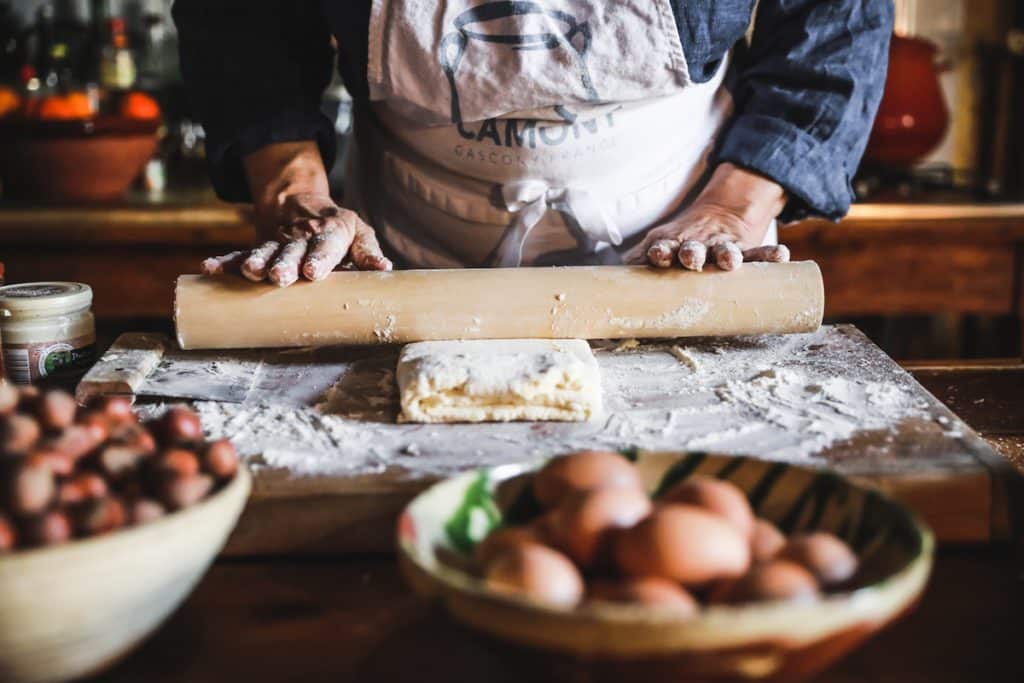 hands rolling a pin over pastry