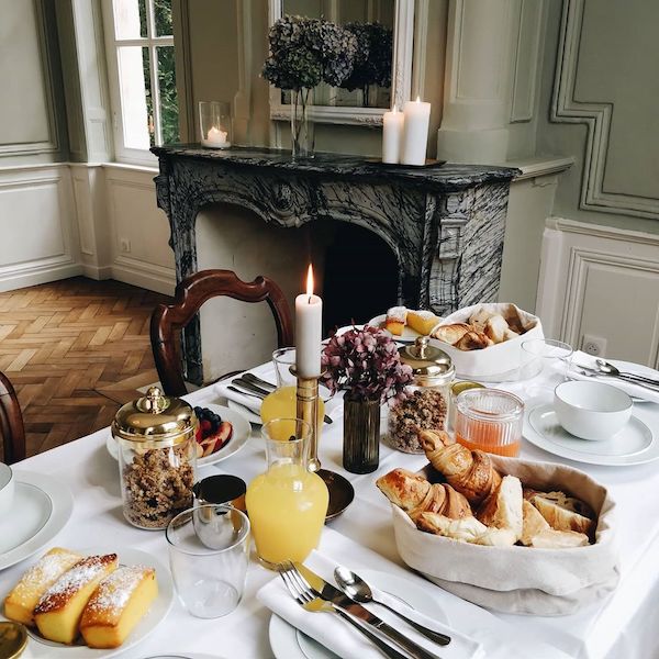breakfast tablescape with pastries, juice and croissant in front of french fireplace