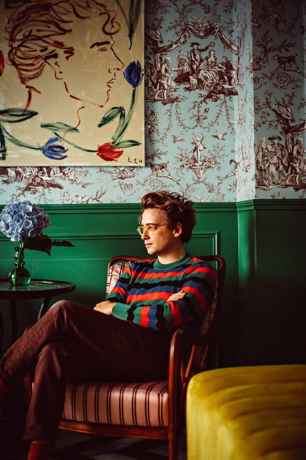 man with glasses in striped red, green and blue sweater sitting in chair