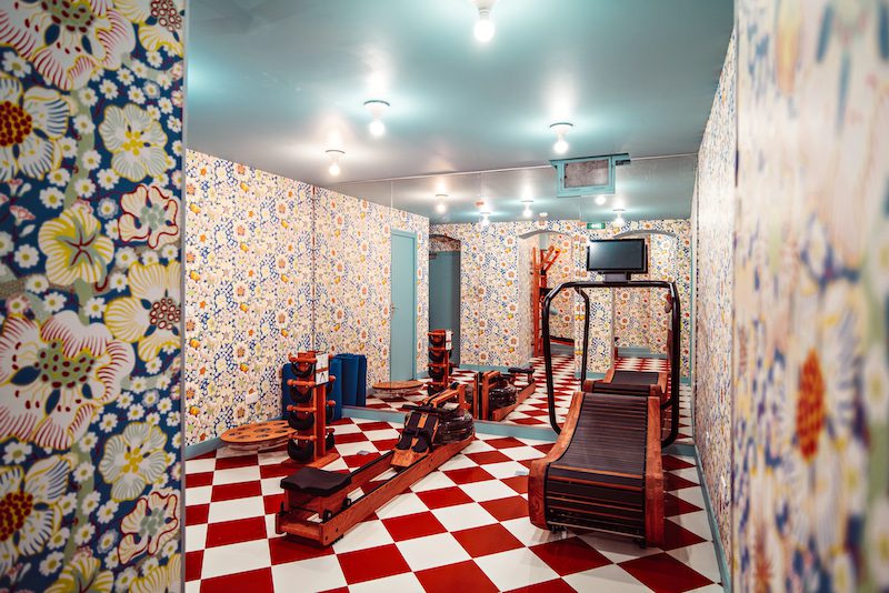 fitness room with red and white checked floor tiling and patterned vintage wallpaper