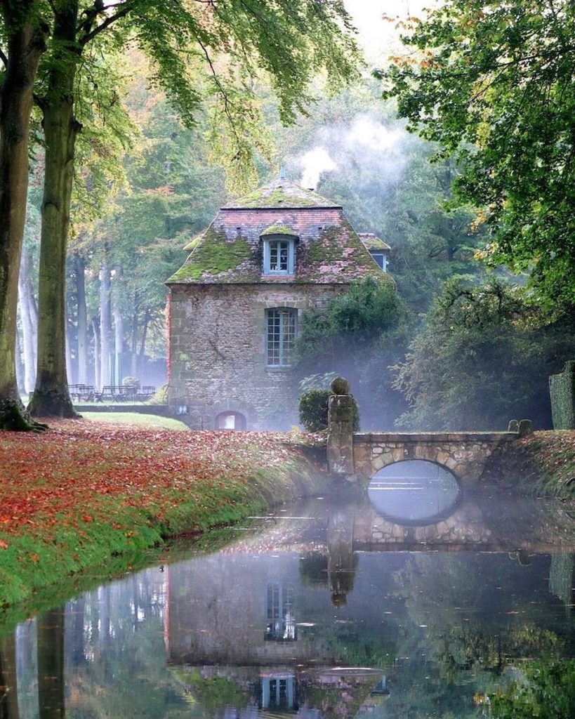 stone home with bridge over a creek in fog