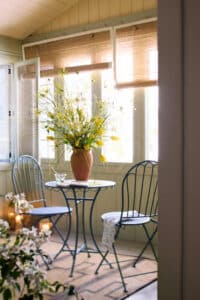 Rustic garden table and chairs in a bright sunroom. 