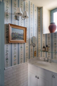 Decluttered French bathroom with original art and ornate wallpaper.