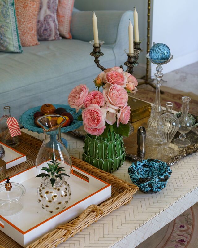 Coffee table with freshly cut flowers, candles, and organized vases.