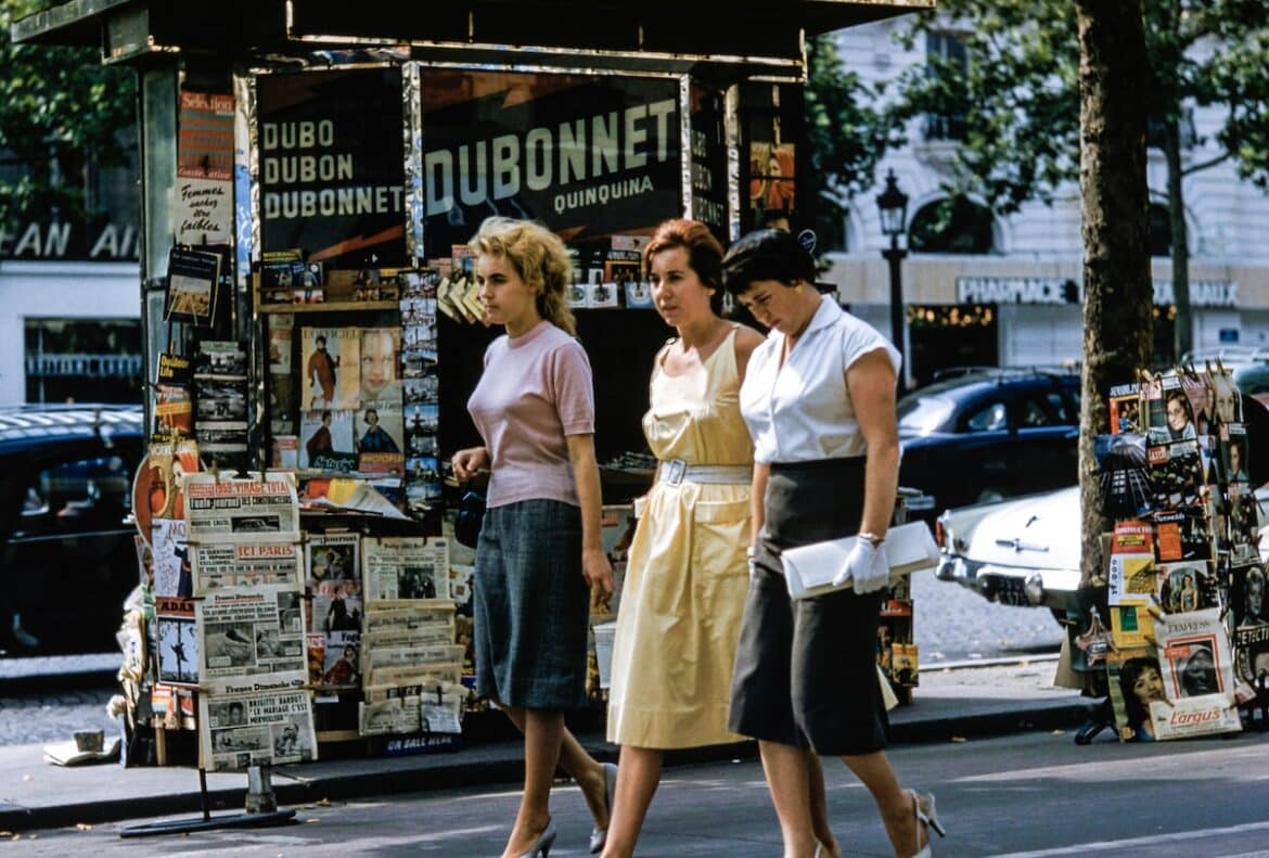 Women walking along a Parisian boulevard wearing 1960's clothing.