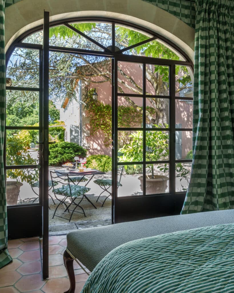 Bedroom overlooking a garden terrace with open French doors.