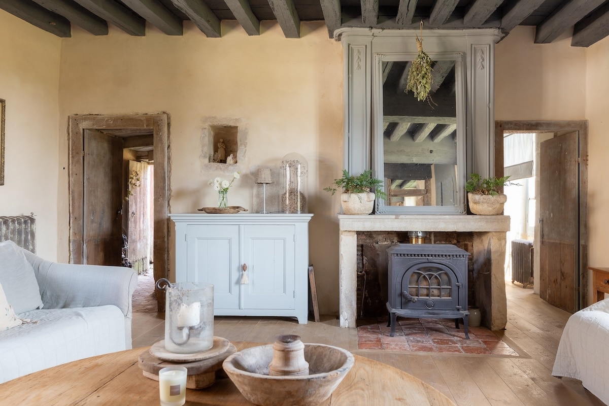Beau Chateau rustic salon interior with a wood stove and bright natural light.