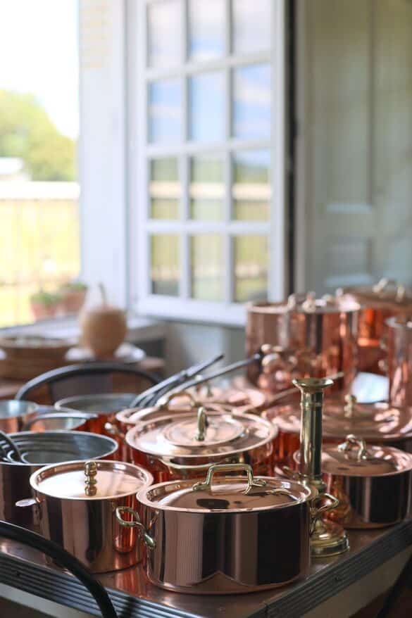 Array of French copper posts and sauce pans on a table.