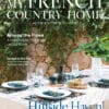 July/August 2026 My French Country Home magazine cover featuring a garden dining table beside a stone wall.