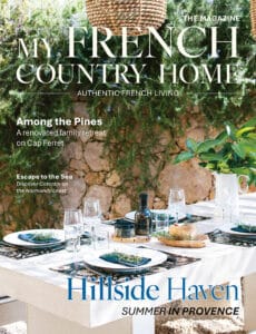July/August 2026 My French Country Home magazine cover featuring a garden dining table beside a stone wall.