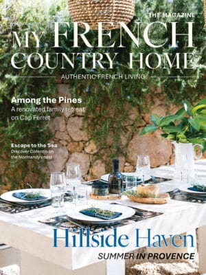 July/August 2026 My French Country Home magazine cover featuring a garden dining table beside a stone wall.