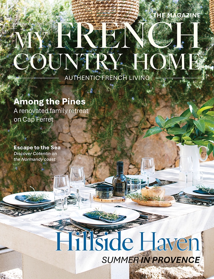 July/August 2026 My French Country Home magazine cover featuring a garden dining table beside a stone wall.
