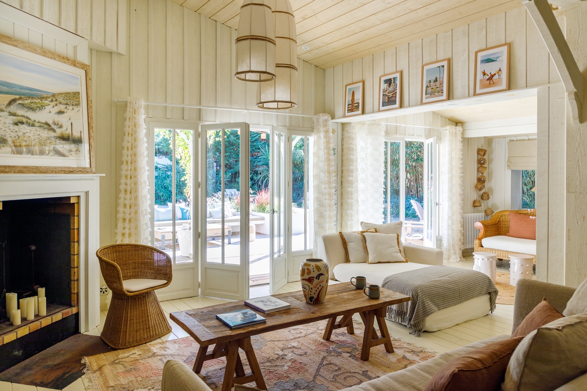 French home interior with white wood paneled walls, framed art, and plush sofas and chairs.