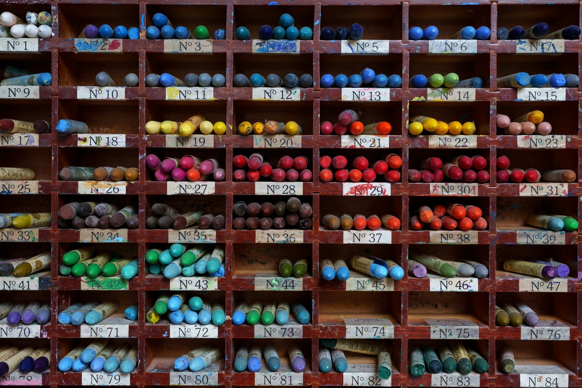 Colorful oil pastels arranged on a wood art organizer.