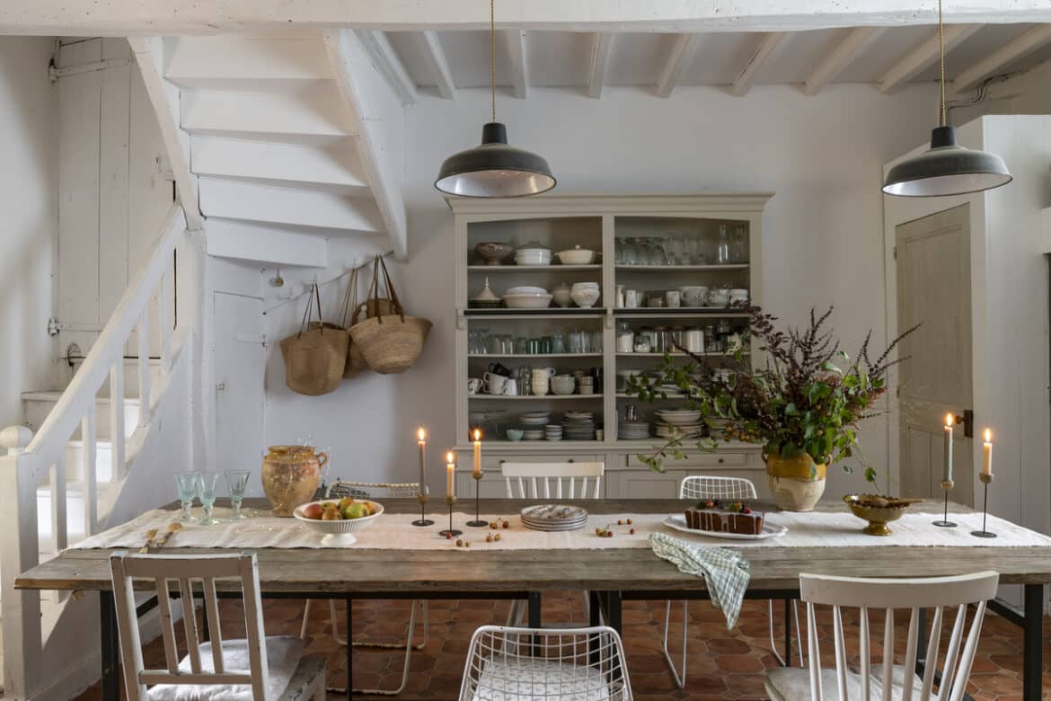 Home dining room interior featuring a rustic farm table, exposed beams, and dinner china.
