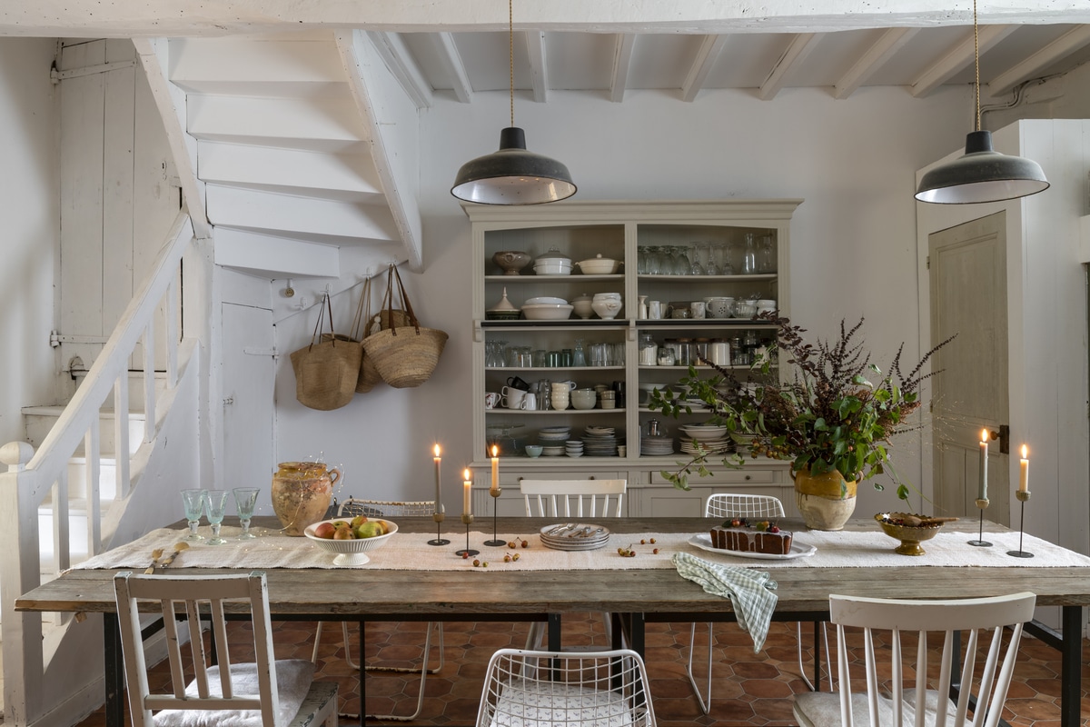 Home dining room interior featuring a rustic farm table, exposed beams, and dinner china.