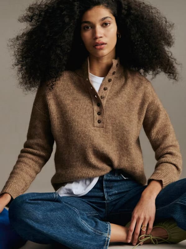 Brown Sézane henley knit sweater styled with a white t shirt and blue jeans.