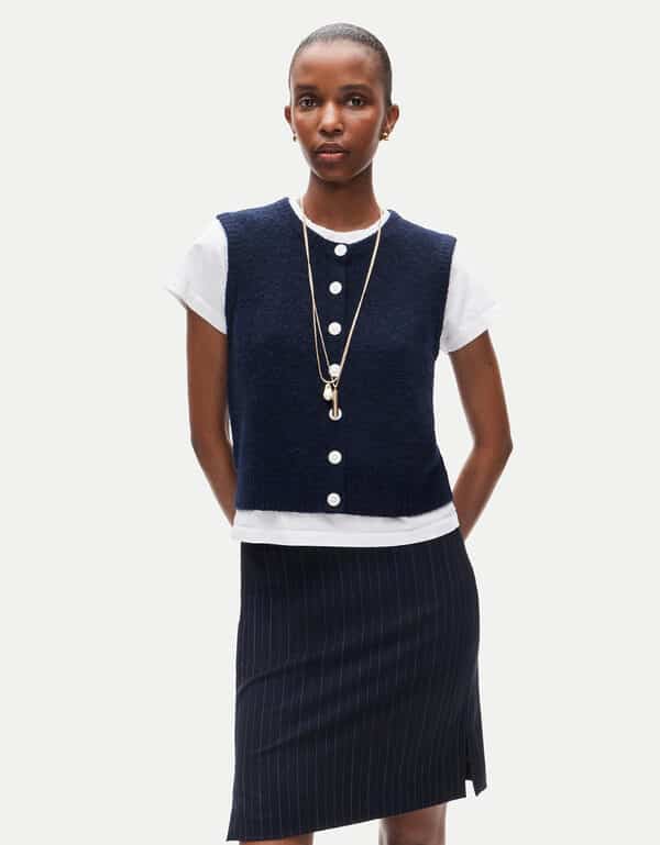 Navy blue alpaca knit J. Crew vest styled over a white t shirt and a pin striped skirt.