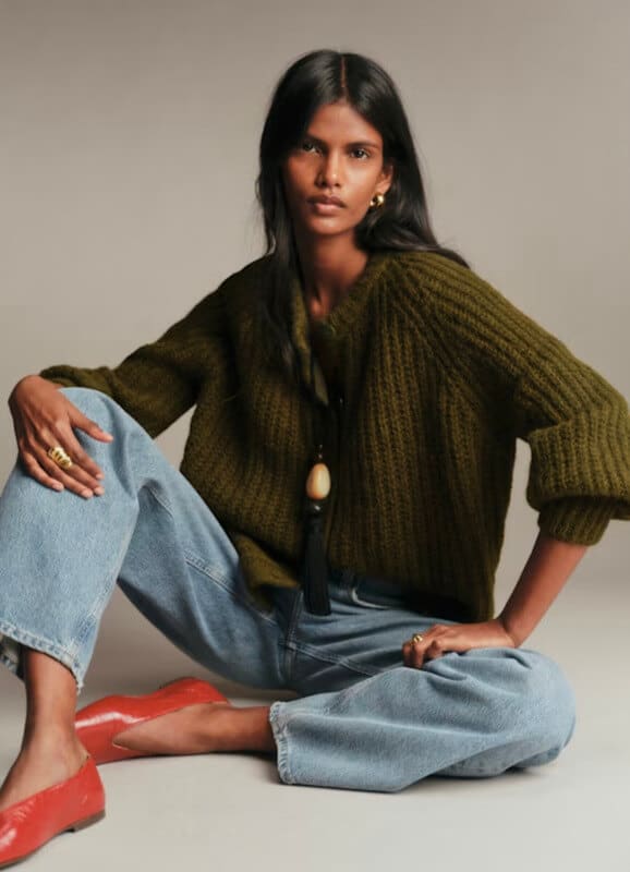Sézane olive green Emile cardigan styled with a chunky necklace, blue jeans, and red ballet flats.