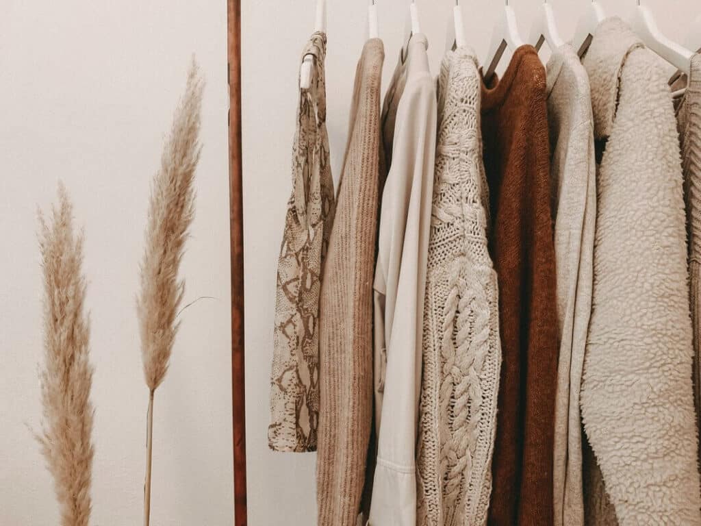 Rack of beige and brown hanging sweaters.