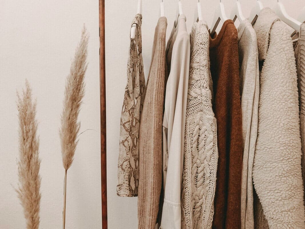 Rack of beige and brown hanging sweaters.