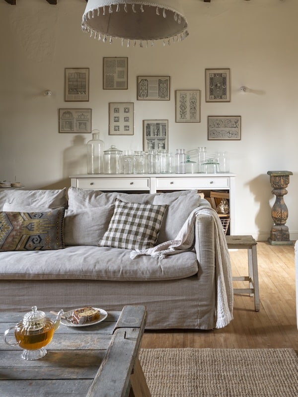 Home salon interior with a linen sofa covered with plush throw pillows and blanket.