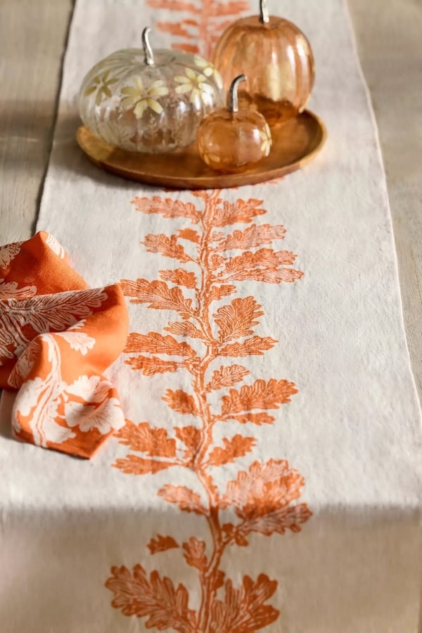 Oak Vine linen table runner with and orange printed branch down the center.