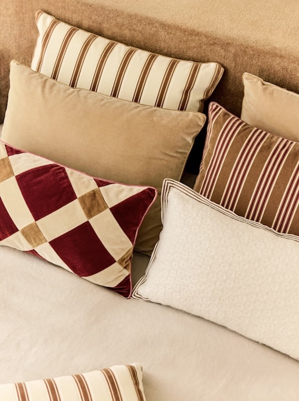 Made bed with brown and Bordeaux striped throw pillows arranged against the headboard.